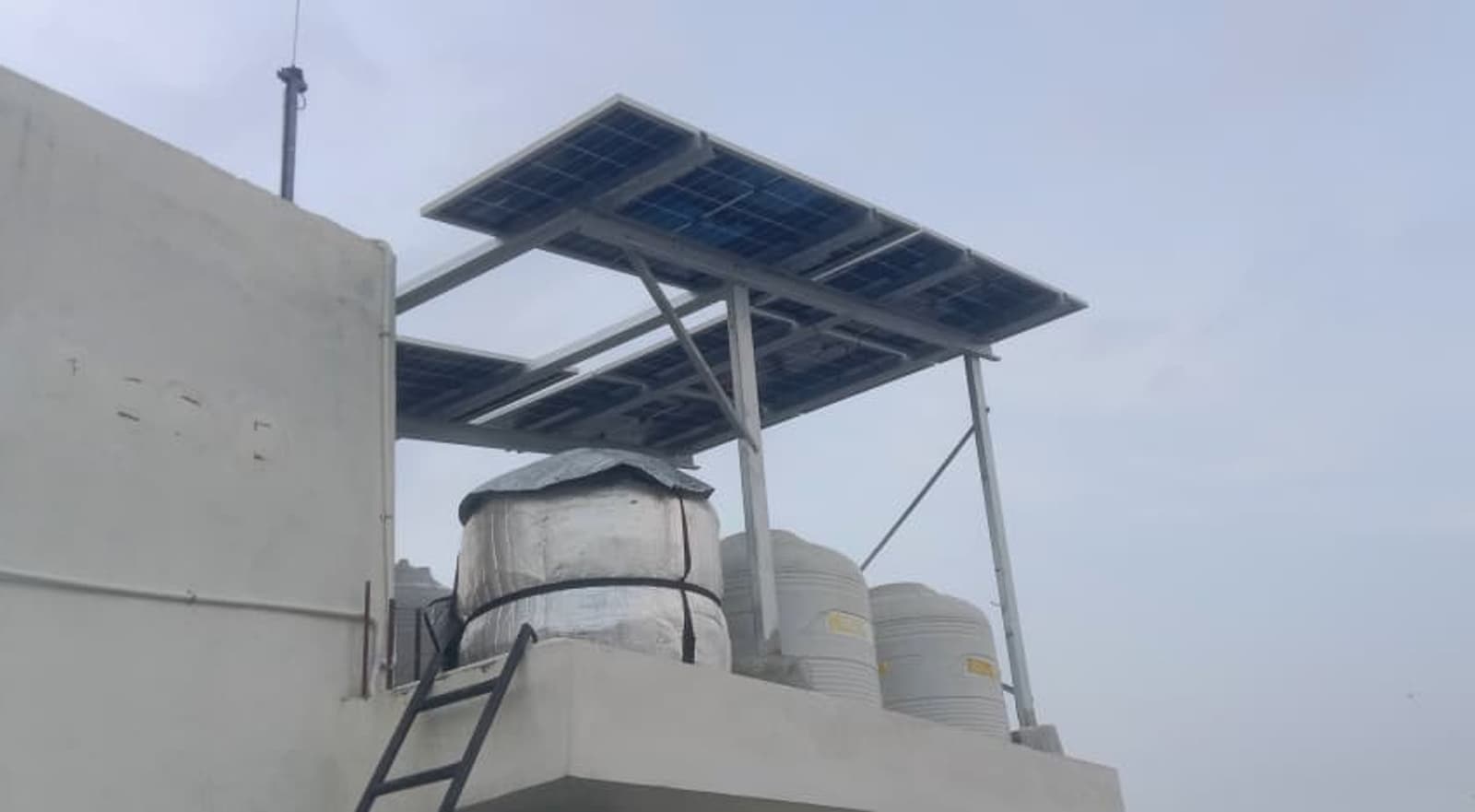 The structure shades the tanks, supporting the customer's argument that the installation would help keep everyone's stored water cooler in summer.